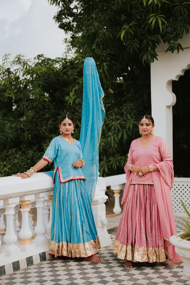 Two women in blue and pink traditional outfits on a terrace