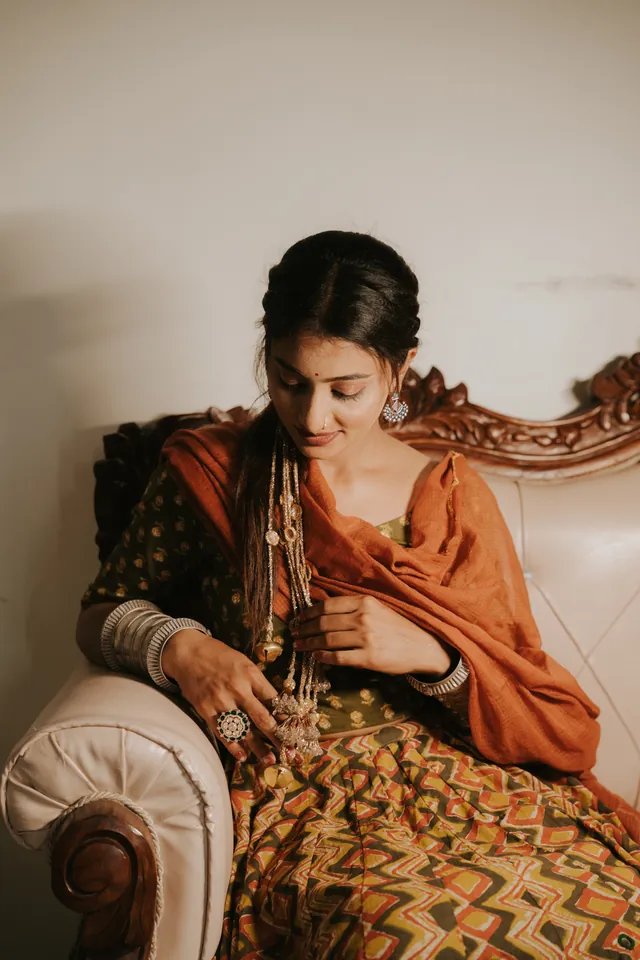 Seated portrait with an orange dupatta and silver jewellery